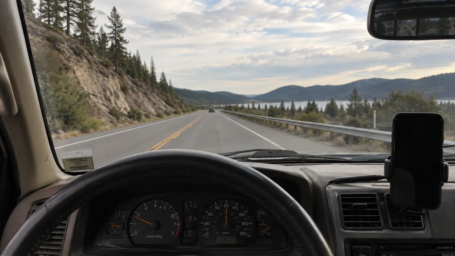 Driver seat view of the road ahead with a phone mount low in the corner of the windshield